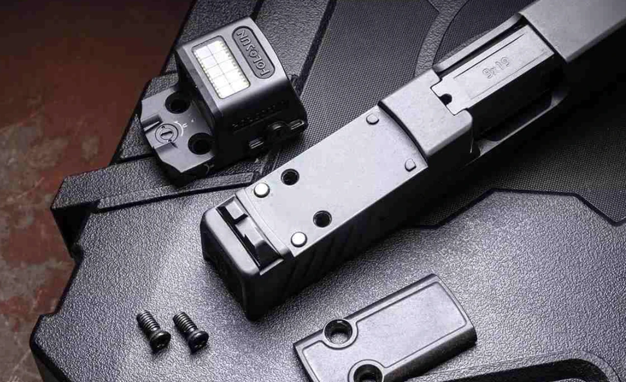 Slide de pistola optic-ready com o recorte e os furos roscados à mostra, tampa de proteção removida, parafusos e micro red dot ao lado