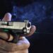Pistola compacta disparando com mira laser verde acesa, feixe visível na fumaça — foto: Viridian Weapon Technologies