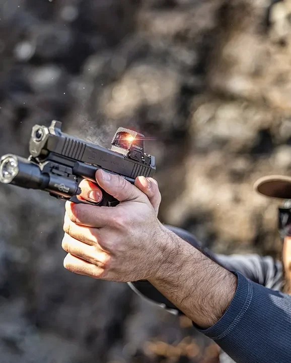 Mão firme em pistola com lanterna e o red dot Vortex Defender-ST aceso